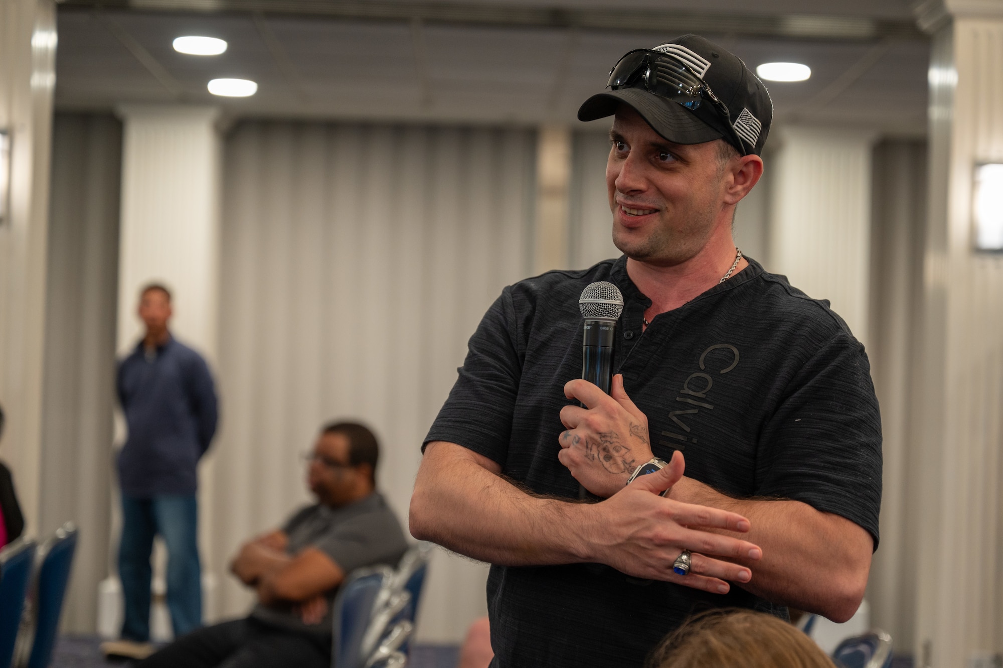 A man holds a microphone and smiles.