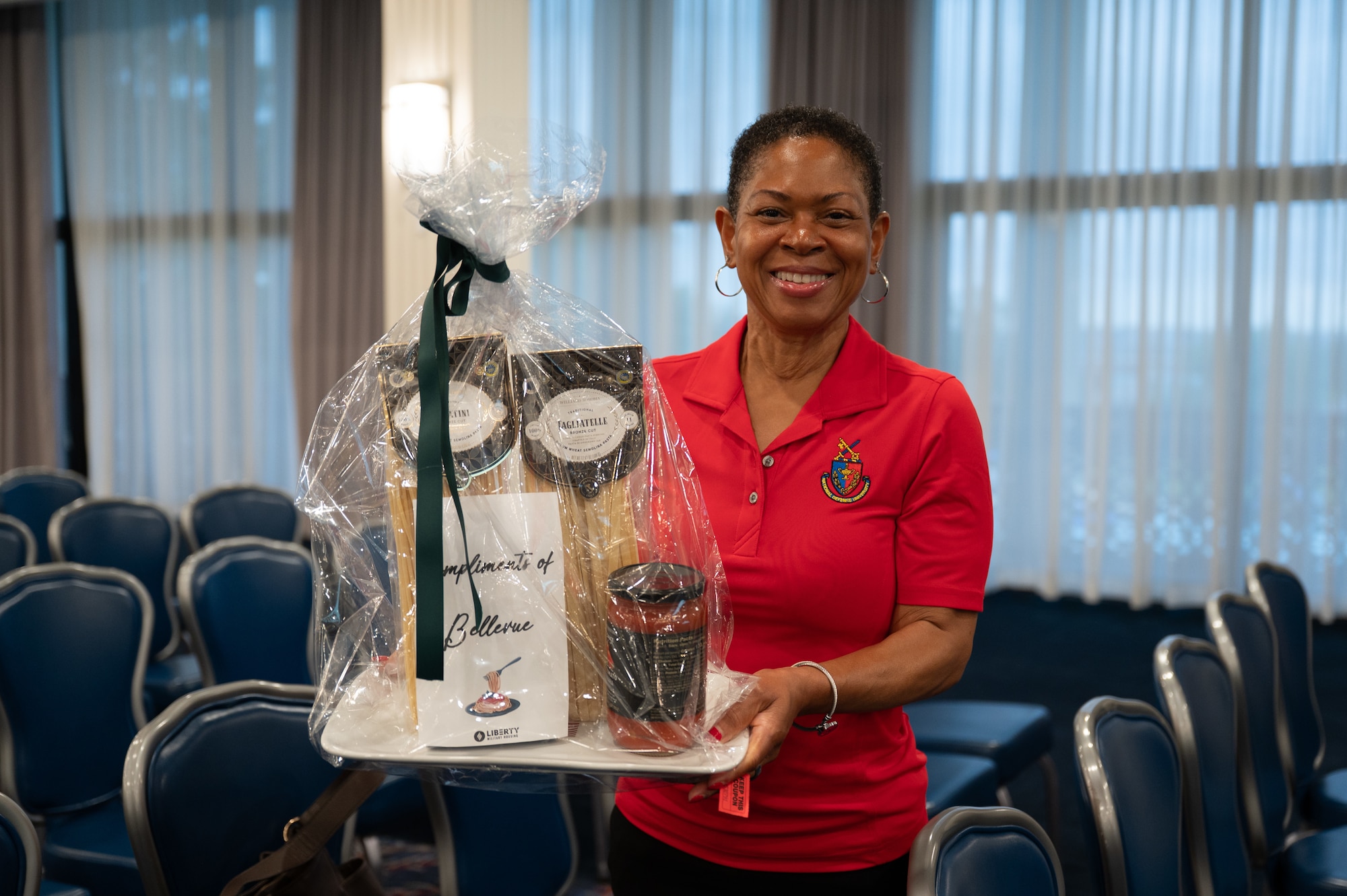 A woman holds a gift basket with household items.
