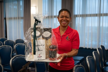A woman holds a gift basket with household items.