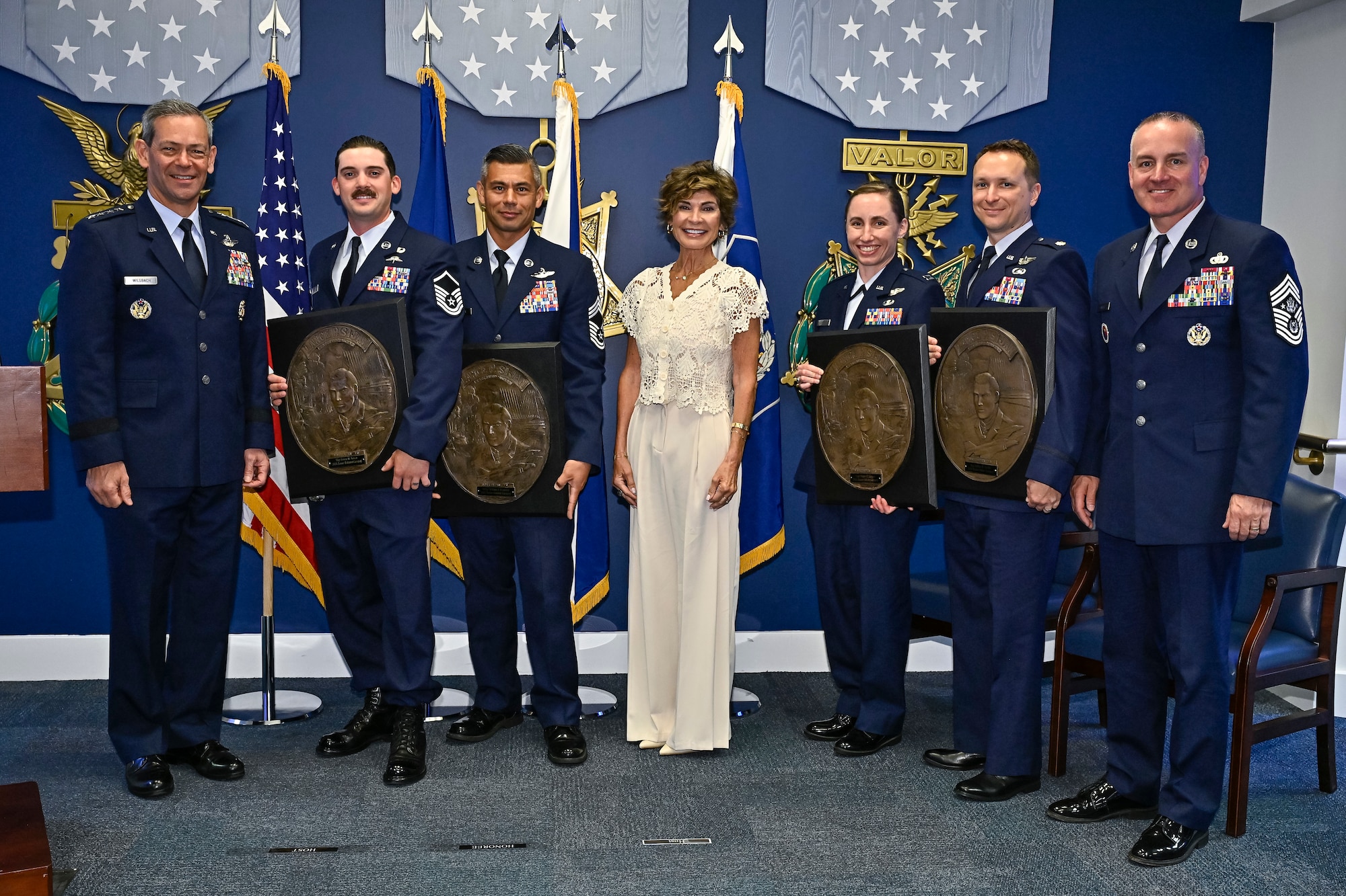 Air Force Chief of Staff Gen. Ken Wilsbach, left, Master Sgt. Steven Nelson, Chief Master Sgt. William Brakebill, Janine Sijan, Capt. Megan Langas, Maj. Joe Goliber and Chief Master Sgt. of the Air Force David Wolfe pose during a ceremony at the Pentagon.