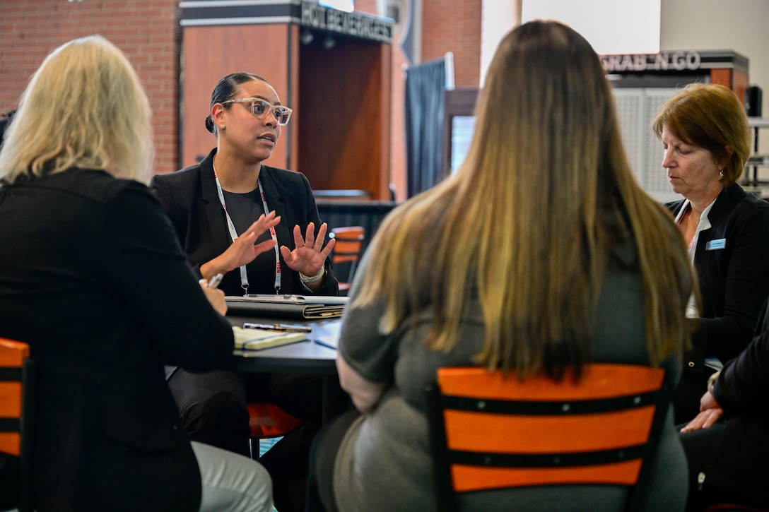 A group of people converse around a table in a cafeteria.