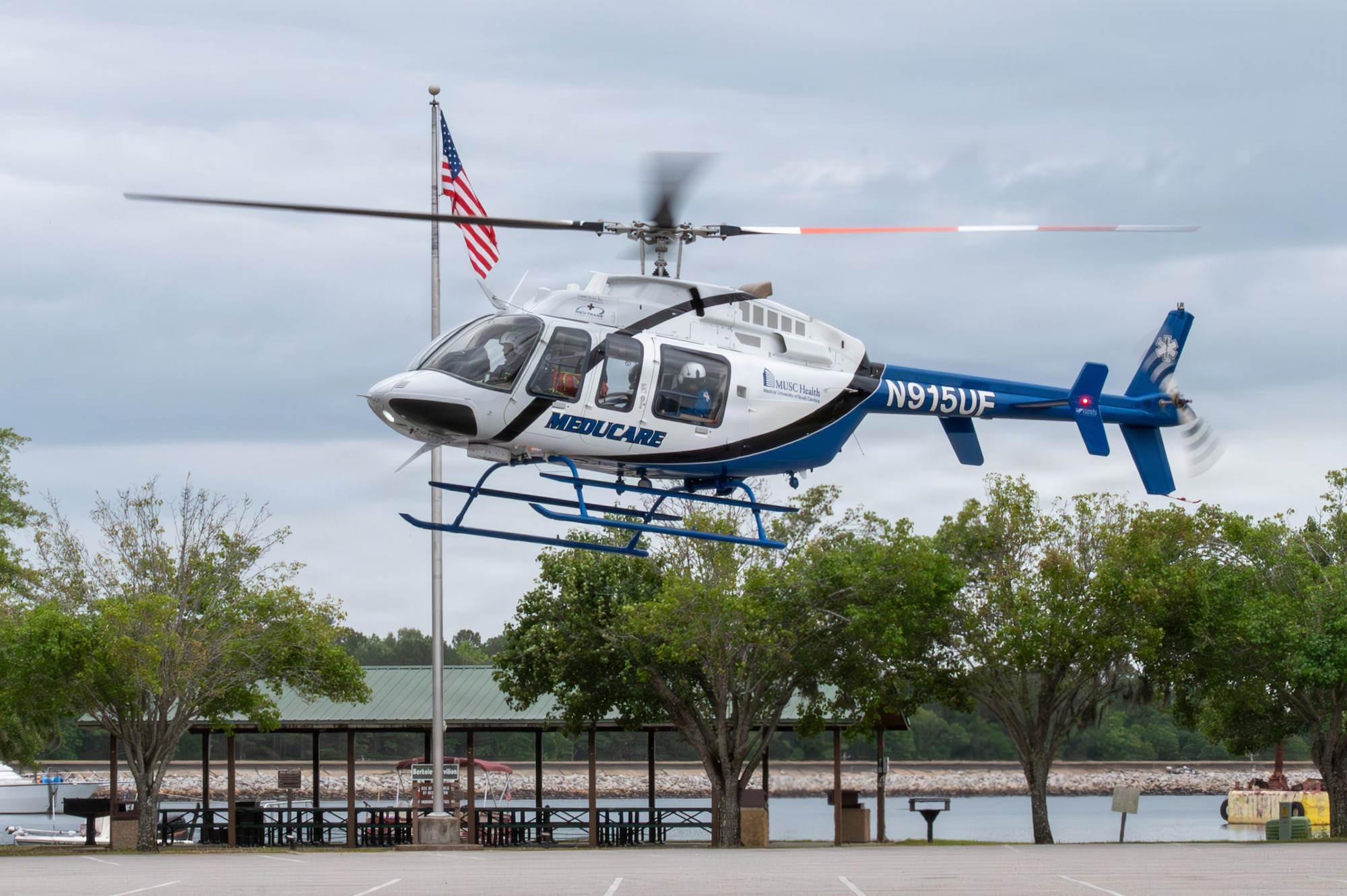 A helicopter prepares to land in a parking lot.