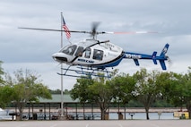 A helicopter prepares to land in a parking lot.