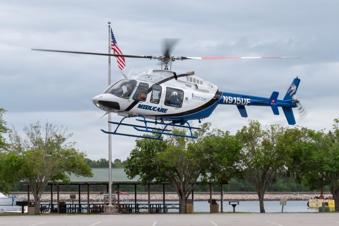 A helicopter prepares to land in a parking lot.