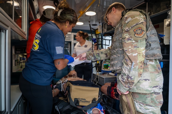 Various Airmen stand around a gurney with a mannequin and various medical equipment performing medical tasks.