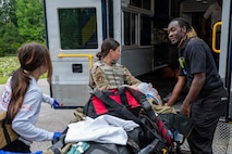 Three people push a gurney with a patient on it into an ambulance.