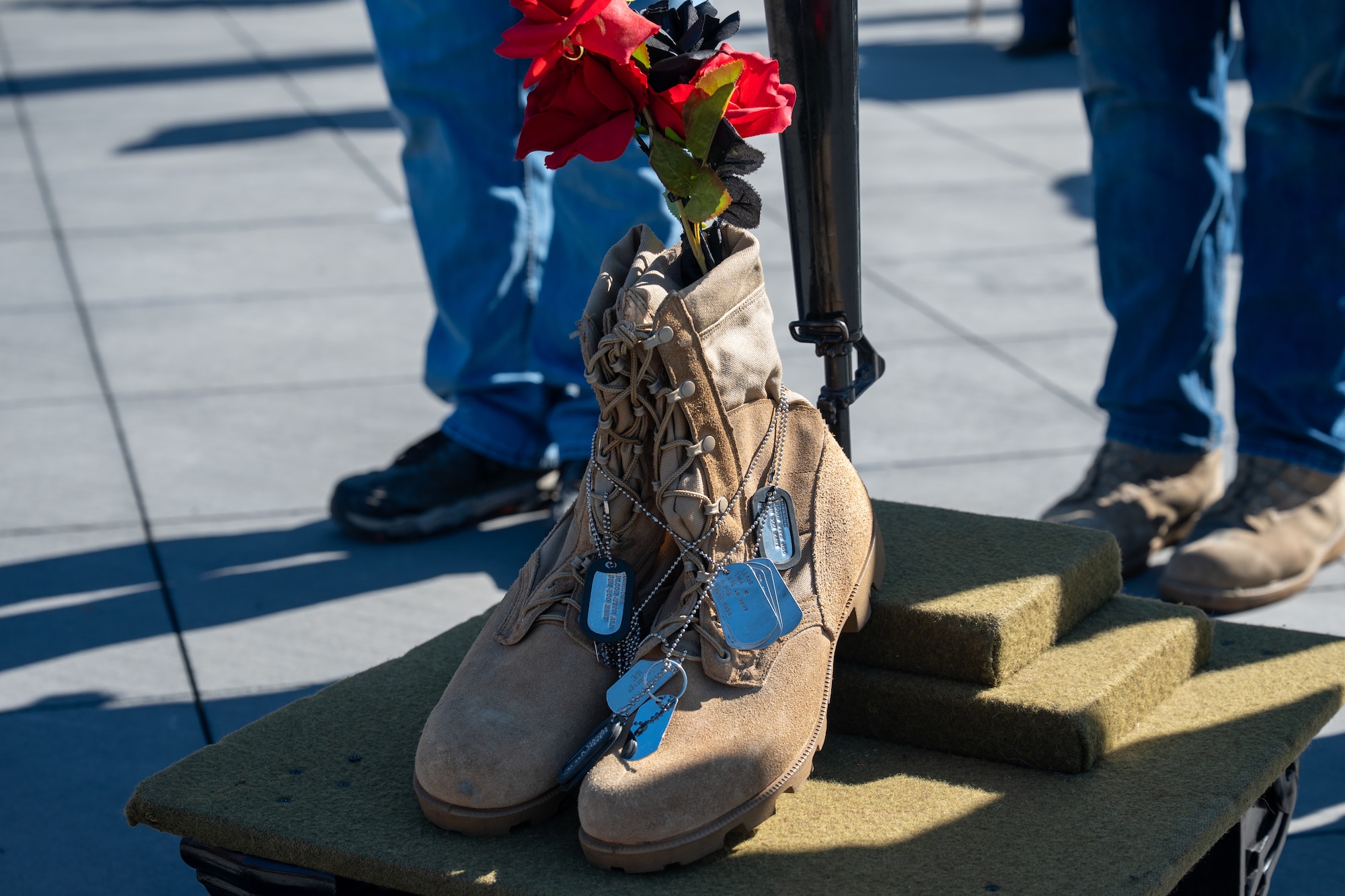 Identification tags drape across a pair of combat boots during the Anchorage Remembers Memorial Day Ceremony at the Delaney Park Strip Veterans Memorial in Anchorage, Alaska, May 25, 2026. The items formed the base of a traditional battlefield cross erected to honor fallen service members. (U.S. Air Force photo by Airman 1st Class Theodore Gowdy)