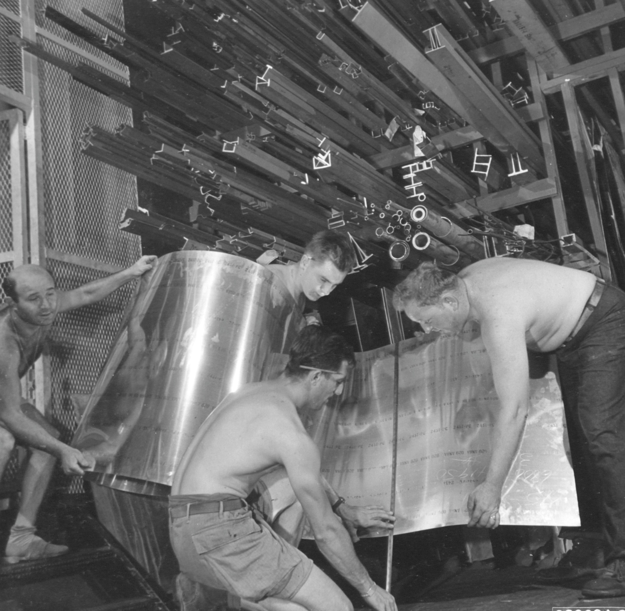 Members of the 1st Aircraft Repair Unit (Floating) measure a piece of sheet metal to be used on a Boeing B-29 Superfortress of the 21st Bomber Command, somewhere in the Pacific.