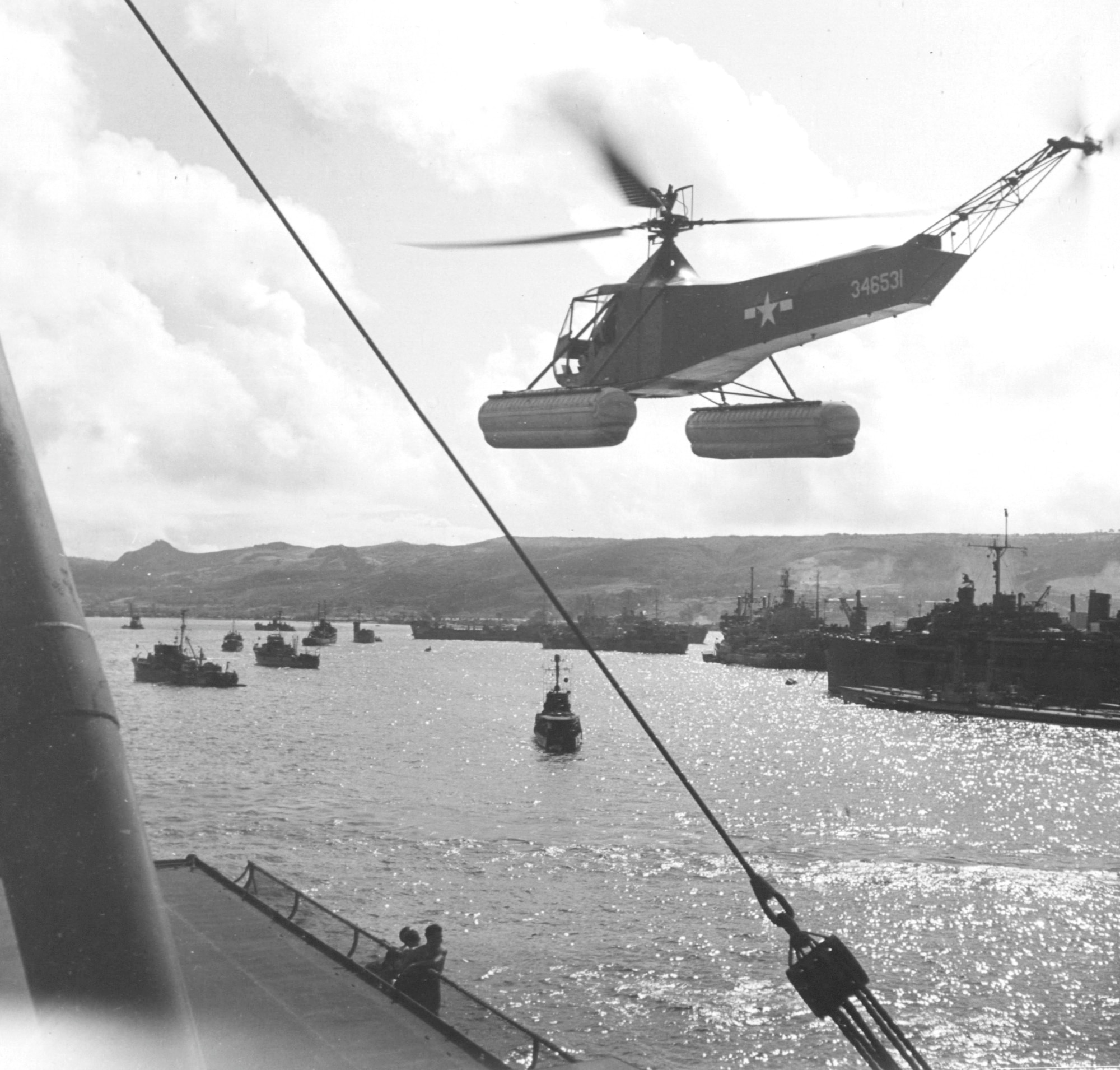 A Sikorsky R-4B Hoverfly hovers near the flight deck of an Aircraft Repair Ship somewhere in the Pacific.