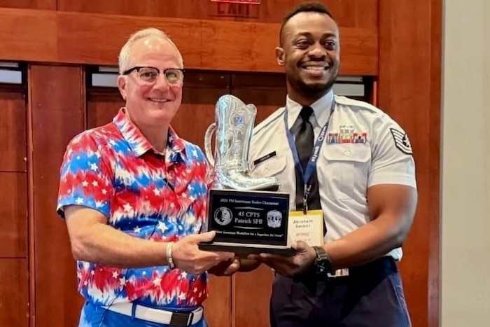 Man presents trophy to Airman