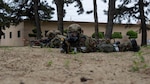 Airmen lay on ground with weapons.
