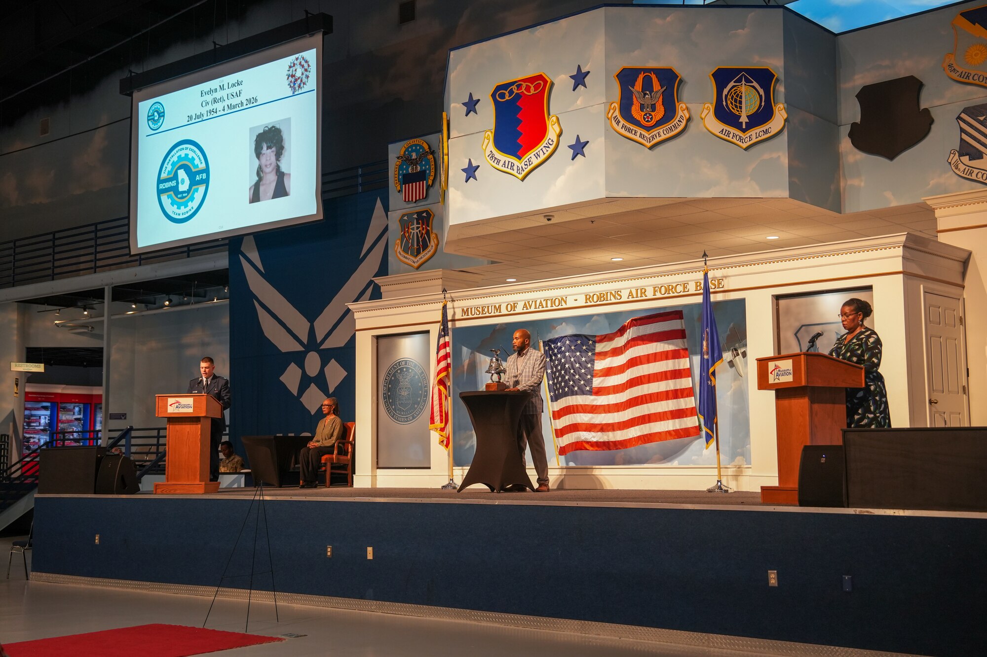 Three people stand on stage