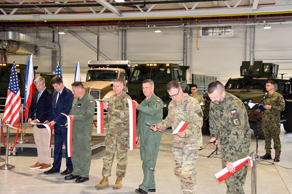 seven men holding sections of a long red and white ribbon they just cut with pairs of small scissors