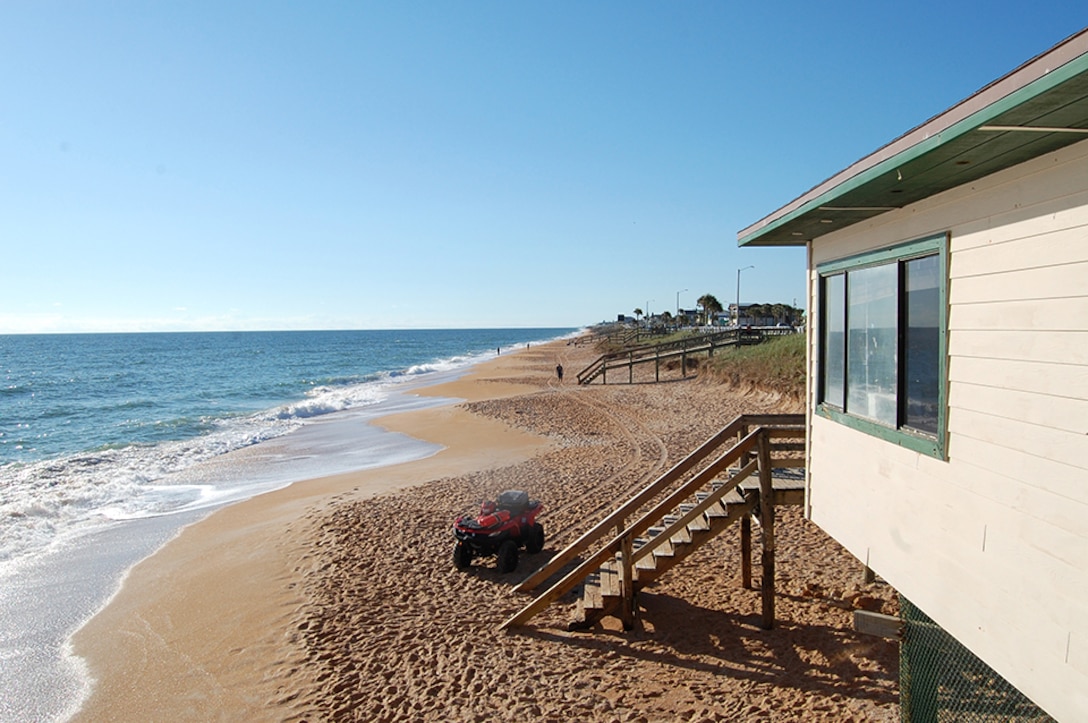 A raised beachfront property a few feet away from a beach shore.