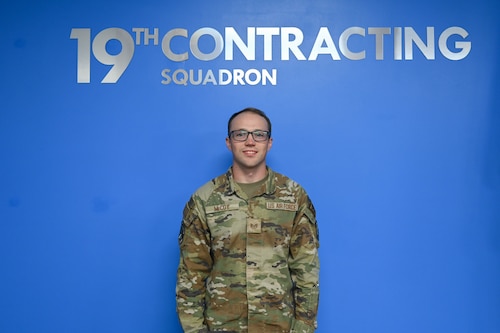 Man poses in front of blue wall.