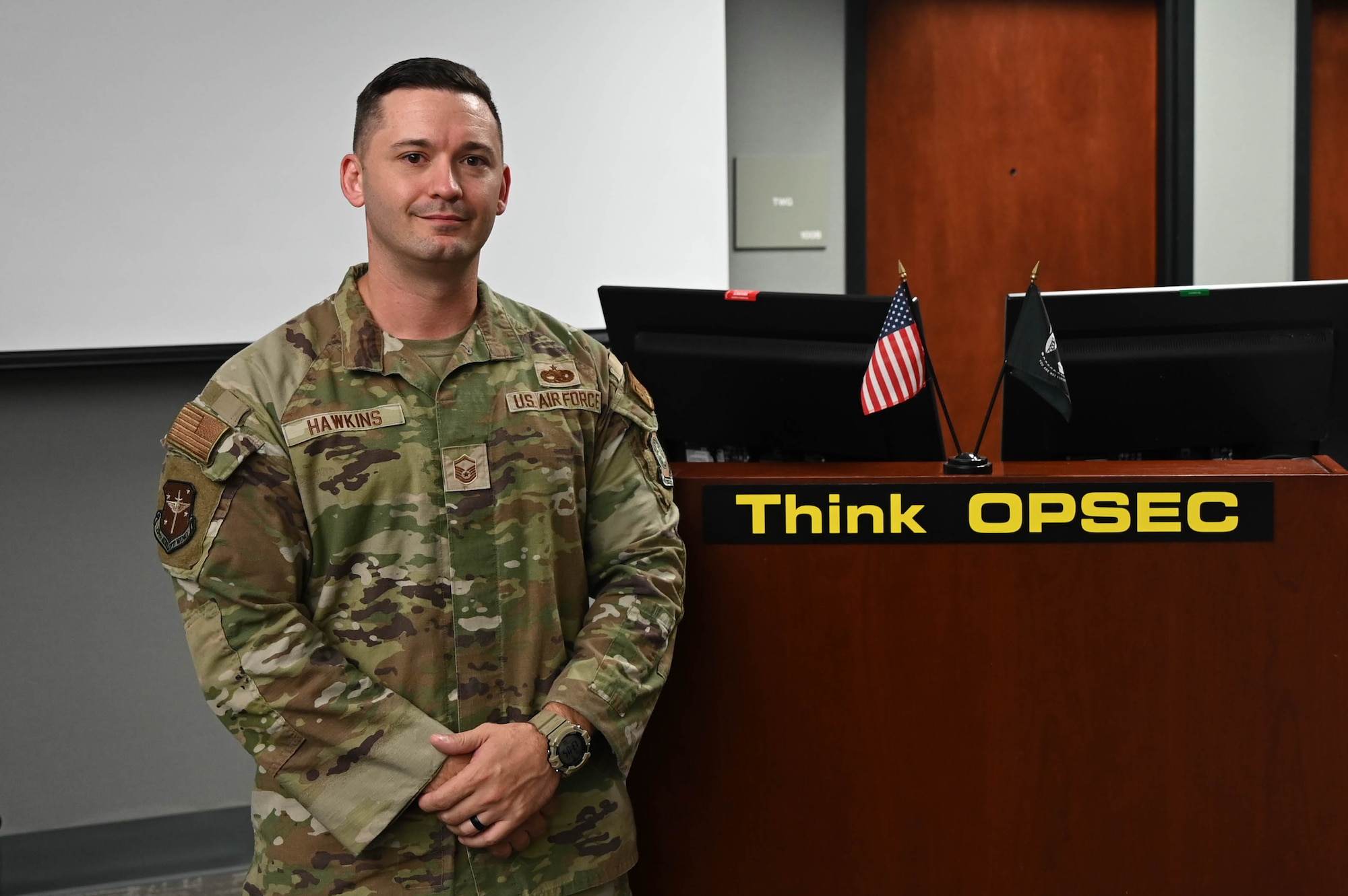 Man poses by desk.