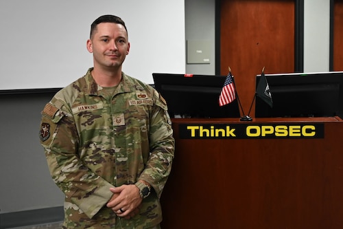 Man poses by desk.