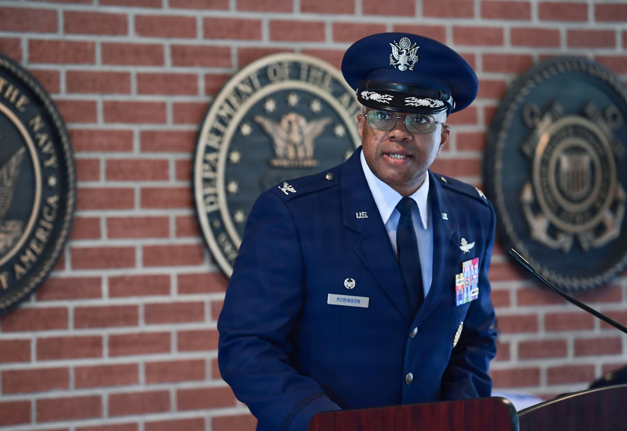 A man in a military uniform speaks from behind a podium.