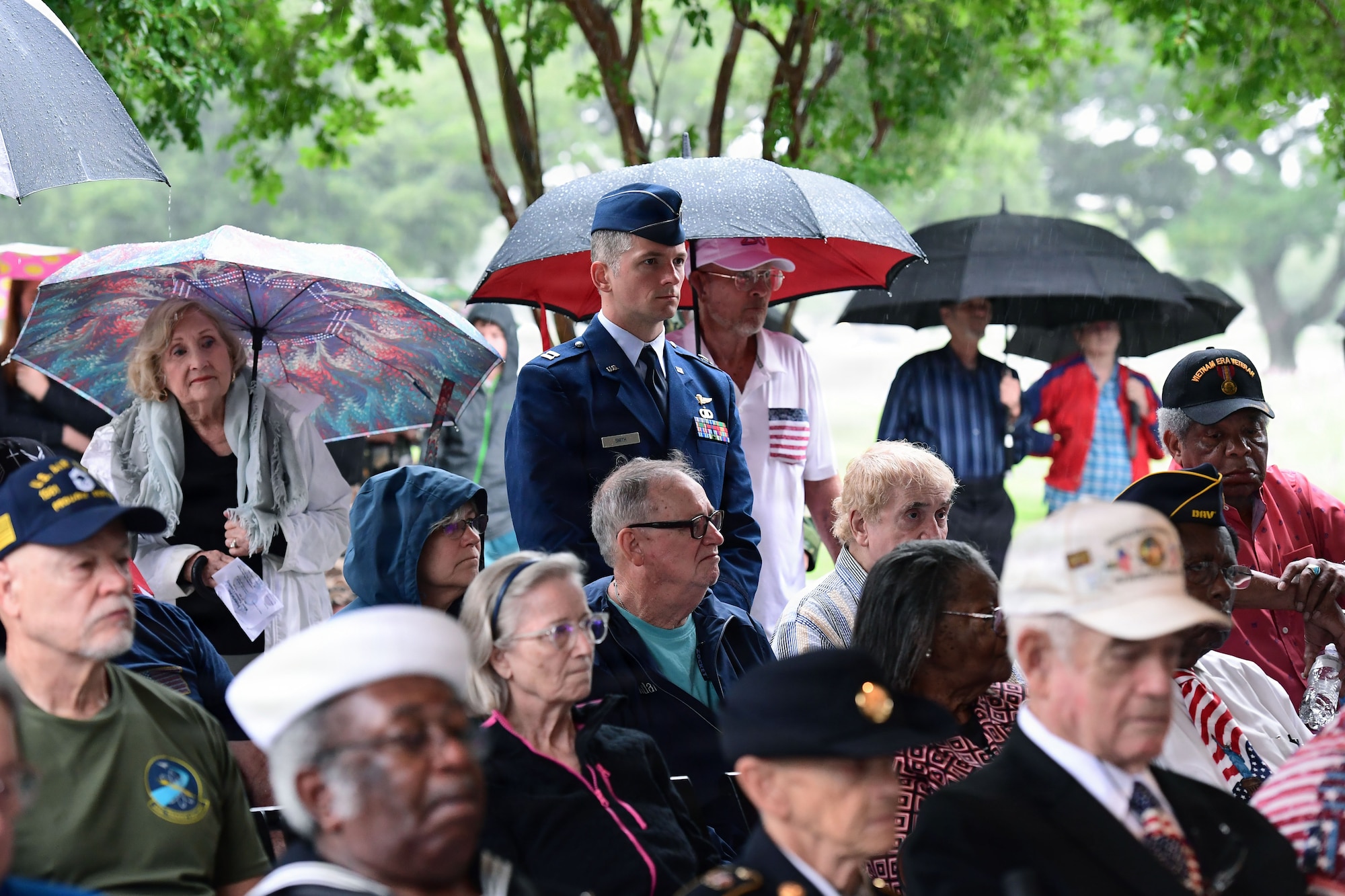 A U.S. Airmen in a military uniform stands in the center of a crowd of people.