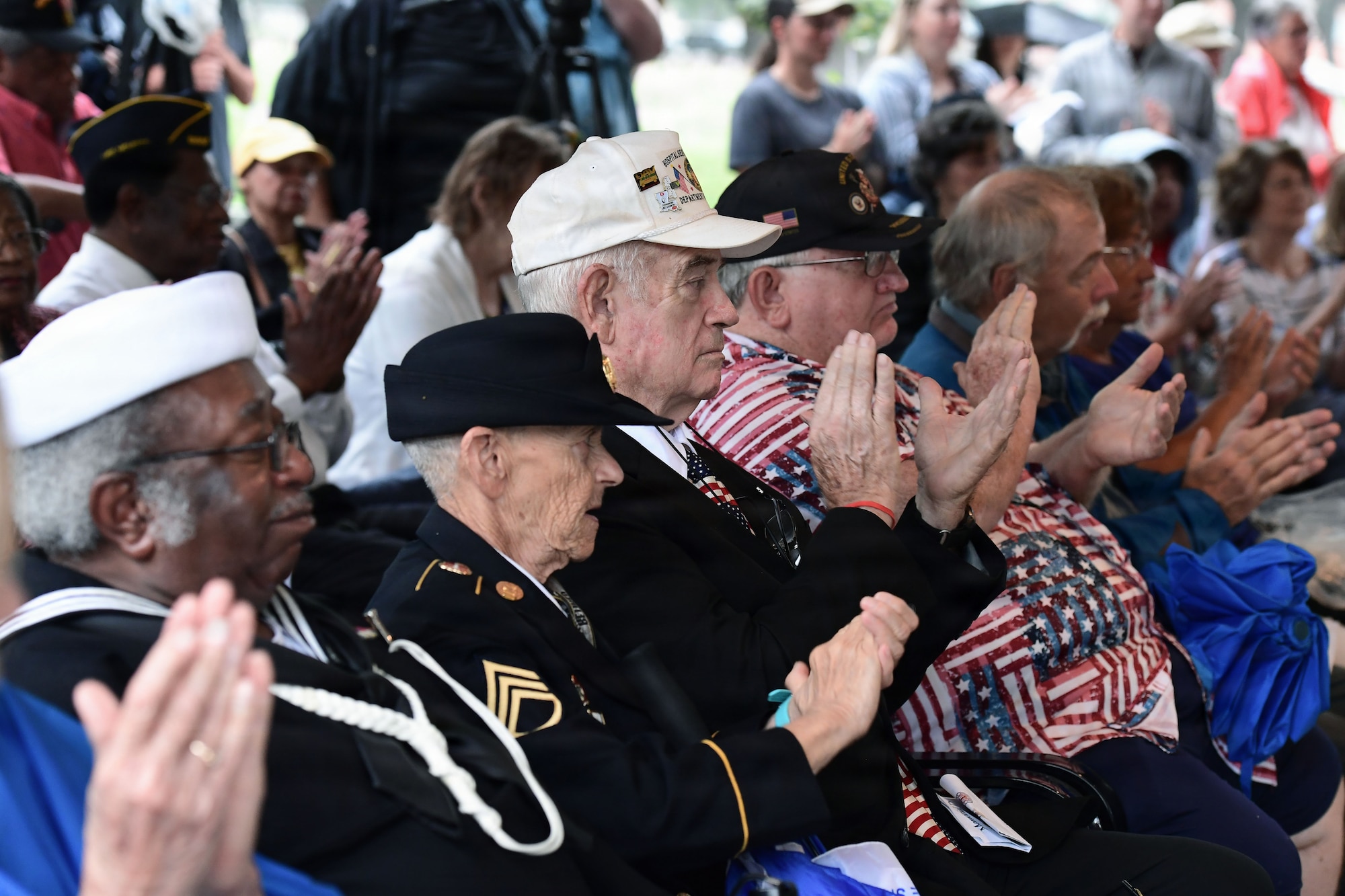 Veterans from various branches of military service applaud.