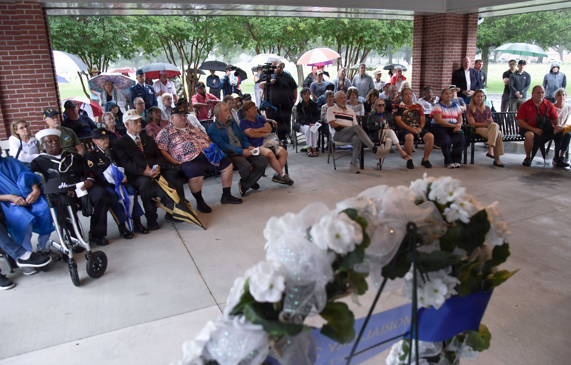 People gather under an awning for a Memorial Day Ceremony.
