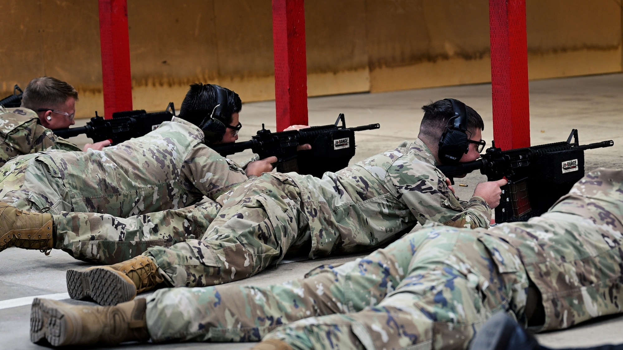A line of Airmen on the firing line shooting M4s in the prone position.