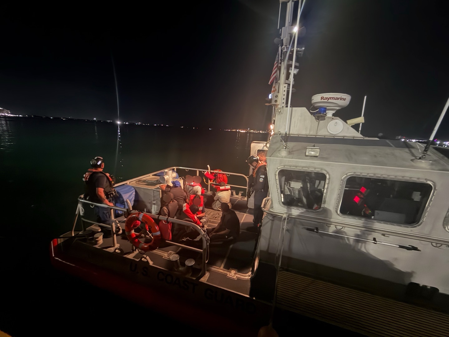 A Coast Guard Station San Juan boat crew oversees a group of eight stowaway aliens apprehended moments earlier aboard the Charlotte Bridge barge as it was being towed into San Juan Harbor, May 22, 2026. The apprehended stowaways were transferred to Customs and Border Protection San Juan Field Office personnel for further processing. This apprehension is part of the Homeland Security Task Force (HSTF) initiative established by Executive Order.  The HSTF is a whole-of-government partnership dedicated to eliminating criminal cartels, foreign gangs, transnational criminal organizations, and human smuggling and trafficking rings operating in the United States and abroad. (U.S. Coast Guard photo)