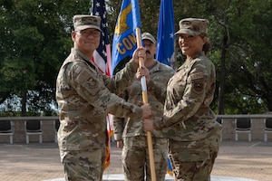 U.S. Air Force Col. Peter Joo, 47th Mission Support Group commander, left, presents the squadron guidon to Maj. Vanessa Valente, incoming 47th Contracting Squadron (CONS) commander, during the 47th CONS change of command ceremony at Laughlin Air Force Base, Texas, May 27, 2026. In a change of command ceremony, the guidon symbolizes the transfer of command, as well as the authority and responsibility associated with it. (U.S. Air Force photo by Airman 1st Class Darryl Keith)