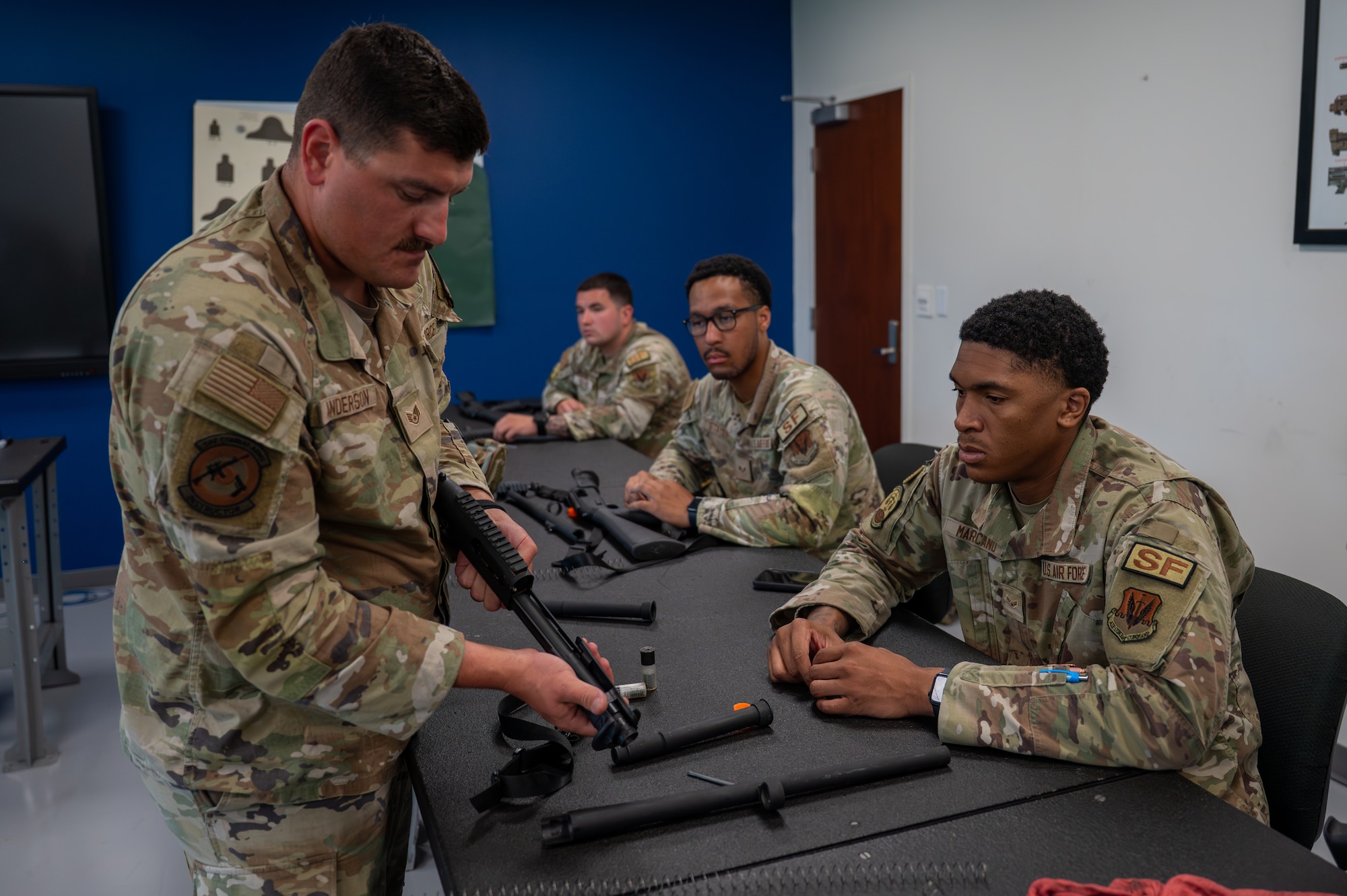 U.S. Air Force Staff Sgt. Matthew Anderson, a 325th Security Forces Squadron combat arms training and maintenance instructor supervisor, demonstrates M870 shotgun assembly to Airman 1st Class Devin Marciano, 325th SFS response force member, during a qualification course at Tyndall Air Force Base, Florida, May 21, 2026. Instructors used the classroom portion to teach weapon safety and mechanics before students transitioned to the range for hands-on tactical application. (U.S. Air Force photo by Airman 1st Class Rosario Garcia)