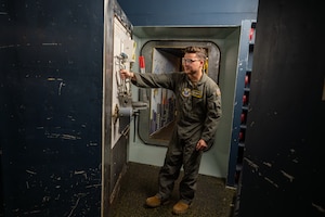 A uniformed man pulls a blast door inside a launch control center.