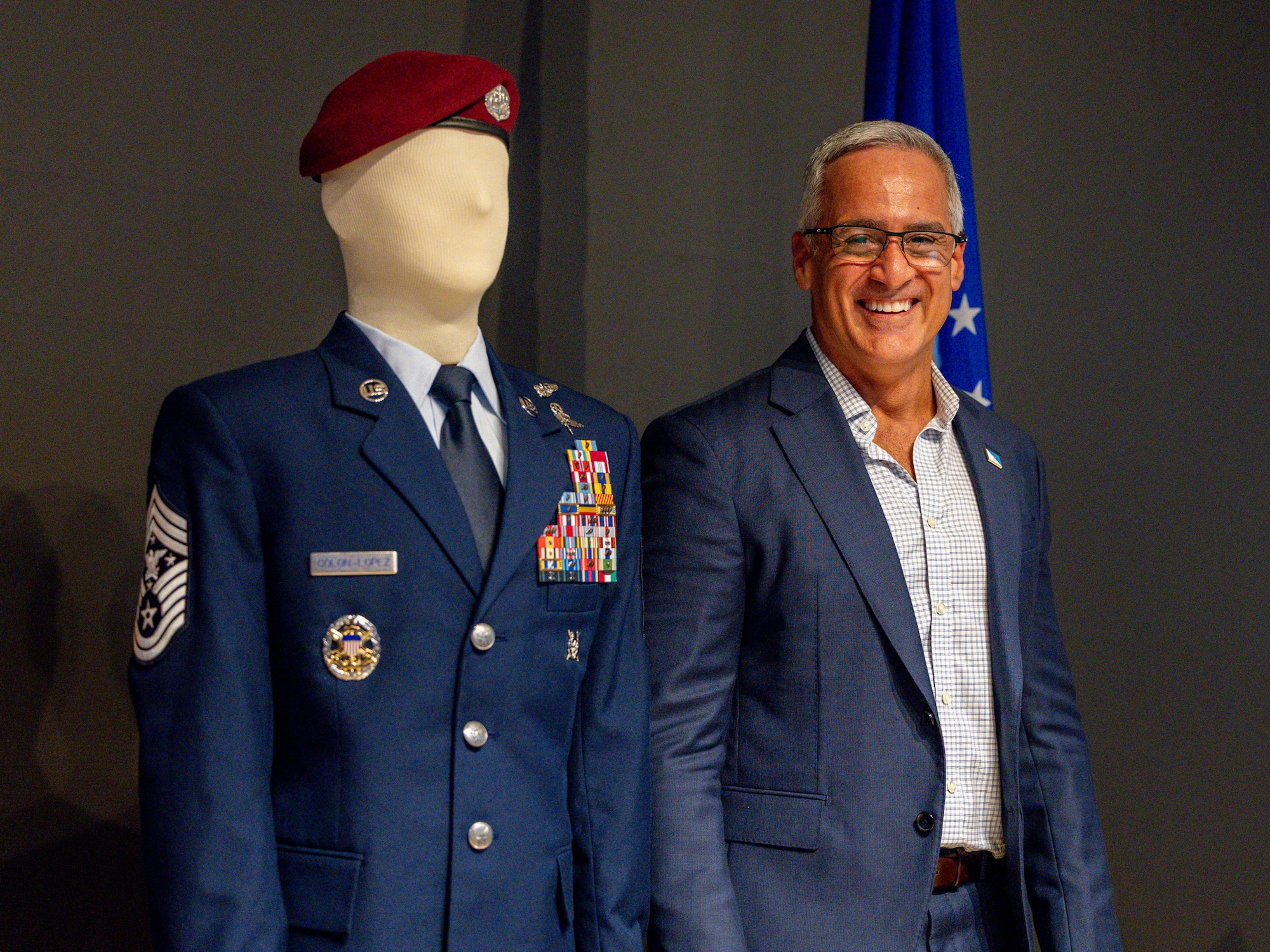 Retired Senior Enlisted Advisor to the Chairman Ramón “CZ” Colón‑López smiles while standing beside a mannequin displaying his service dress during the dedication of the Colón‑López Noncommissioned Officer Academy Auditorium at Sheppard Air Force Base, Texas, May 27, 2026.