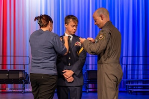 Col. Thomas Tauer, 412th Test Wing commander, and his wife, Janet Tauer, pin rank insignia on their son, Cadet Tech. Sgt. Thomas Tauer, during the annual Air Force Junior ROTC ceremony at Desert Junior-Senior High School on Edwards Air Force Base, Calif., May 28. (U.S. Air Force photo by Christian Raterman)