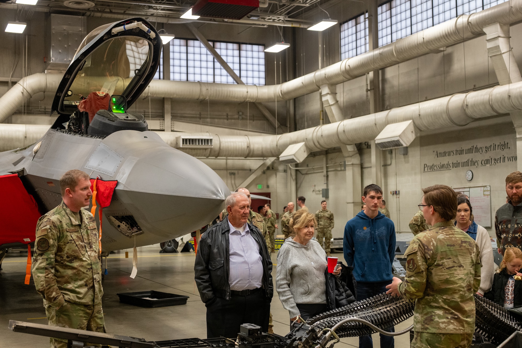A U.S. Air Force Airman assigned to the 3rd Munitions Squadron, explains how ammunition is fed into the F-22 Raptor's M61A2 20mm Gatling gun system during a Gold Star family tour at Joint Base Elmendorf-Richardson, Alaska, May 21, 2026. Colville detailed the complex linkless ammunition handling system that prevents jams during high-rate firing maneuvers. This joint-base event brought together Army and Air Force personnel to offer support, fellowship and technical insight to families of fallen service members. (U.S. Air Force photo by Airman 1st Class Theodore Gowdy)