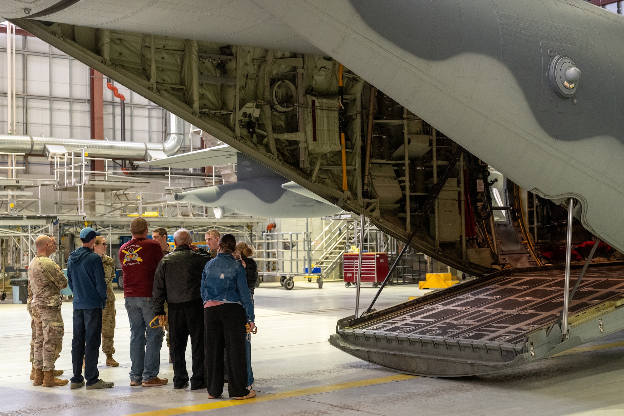 A Gold Star family and tour escorts stand before the loading ramp of an Alaska Air National Guard C-130J Super Hercules aircraft inside a hangar at the 176th Wing on Joint Base Elmendorf-Richardson, Alaska, May 21, 2026. The 3rd Wing-led tour provided the group an immersive look into the hangar environment and the inter-service teamwork required to maintain regional readiness. This joint-base event brought together Army and Air Force personnel to offer support, fellowship and technical insight to families of fallen service members. (U.S. Air Force photo by Airman 1st Class Theodore Gowdy)