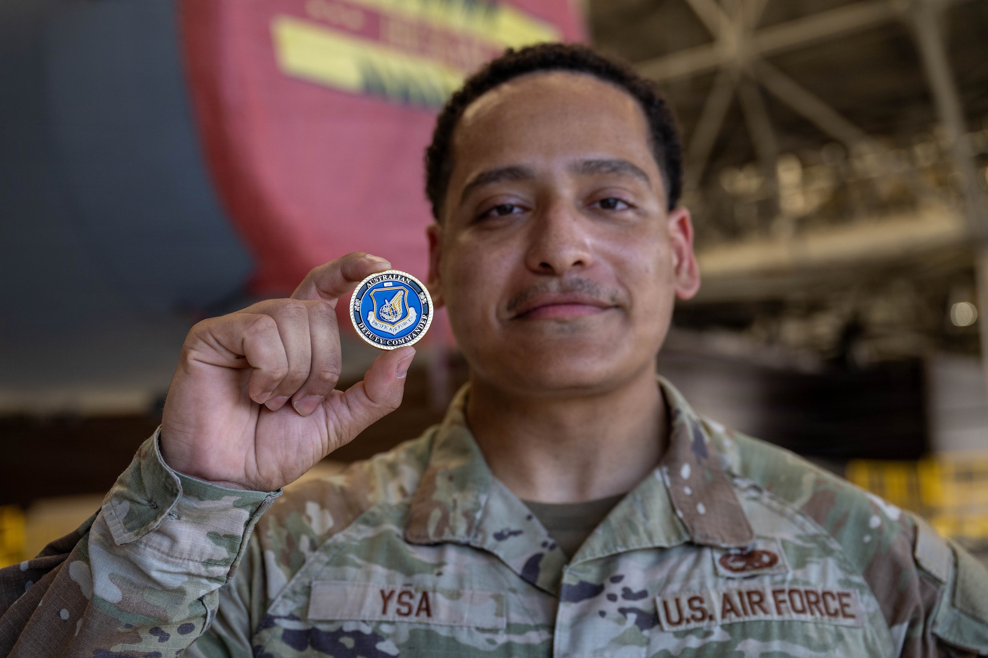 U.S. Air Force Staff Sgt. Jeremy Javier Ysa, 15th Aircraft Maintenance Squadron technician, holds a coin at Joint Base Pearl Harbor-Hickam, May 19, 2026. Ysa was coined by Royal Australian Air Force Air Vice-Marshal David Titheridge, Pacific Air Forces deputy commander, for distinguished performance in the execution of his duties. (U.S. Air Force photo by Senior Airman Lauren Torres)