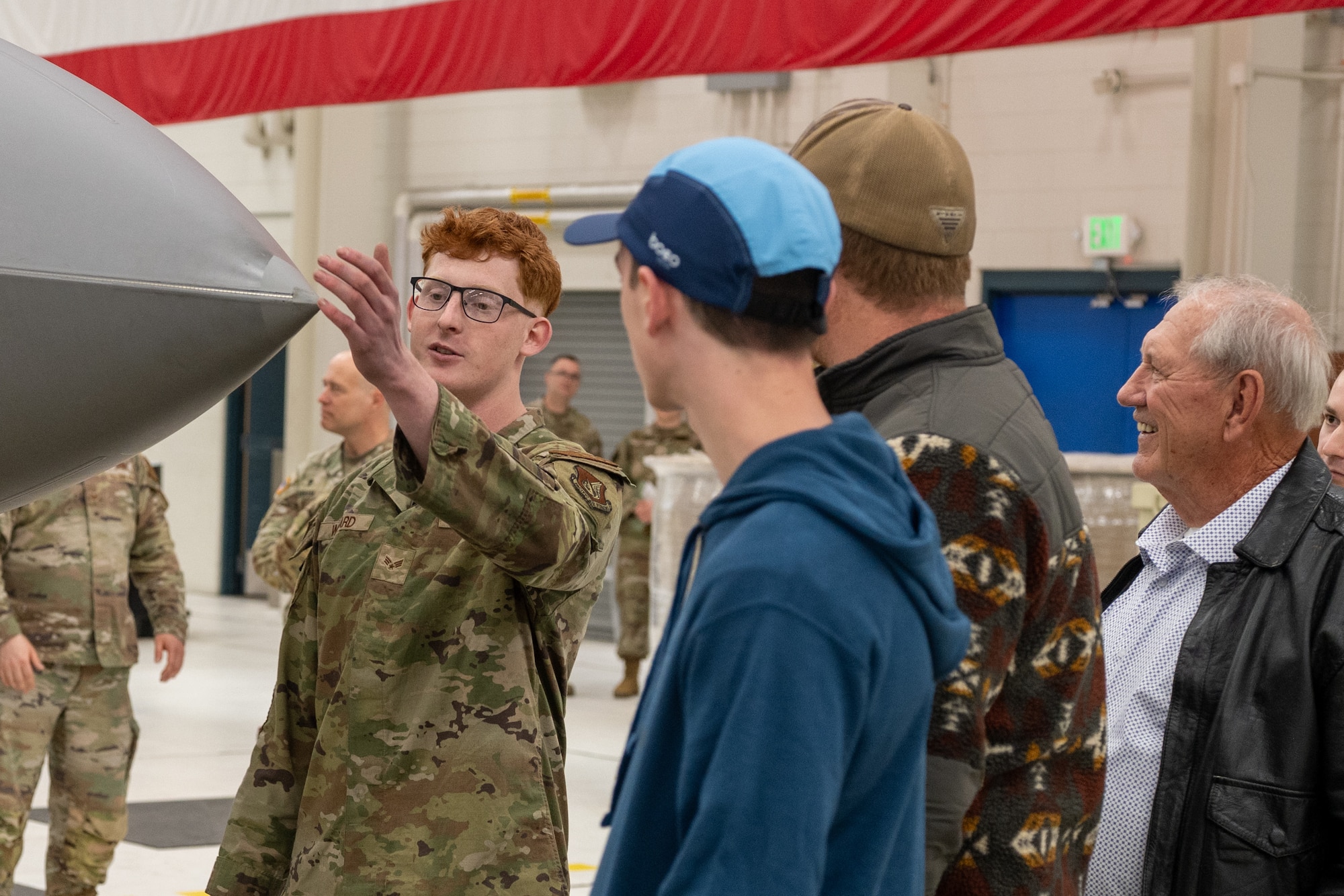 A U.S. Air Force Airman assigned to the 525th Aircraft Maintenance Unit, talks about the 5th-generation stealth capabilities of an F-22 Raptor with a Gold Star family during a base tour at Joint Base Elmendorf-Richardson, Alaska, May 21, 2026. Willard highlighted how the aircraft's specialized radar-absorbent materials and structural design minimize its radar cross-section to maintain air superiority. This joint-base event brought together Army and Air Force personnel to offer support, fellowship and technical insight to families of fallen service members. (U.S. Air Force photo by Airman 1st Class Theodore Gowdy)