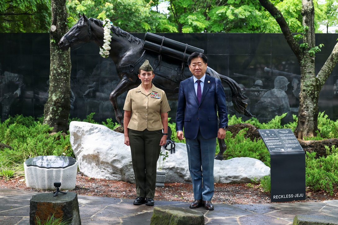 Maj. Gen. Valerie A. Jackson and Gov. Oh Young-hun pose in front of a Staff Sgt. Reckless statue during a wreath-laying ceremony in Jeju City.