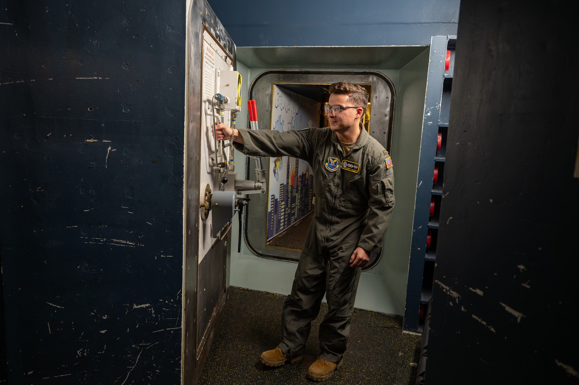 A uniformed man pulls a blast door inside a launch control center.