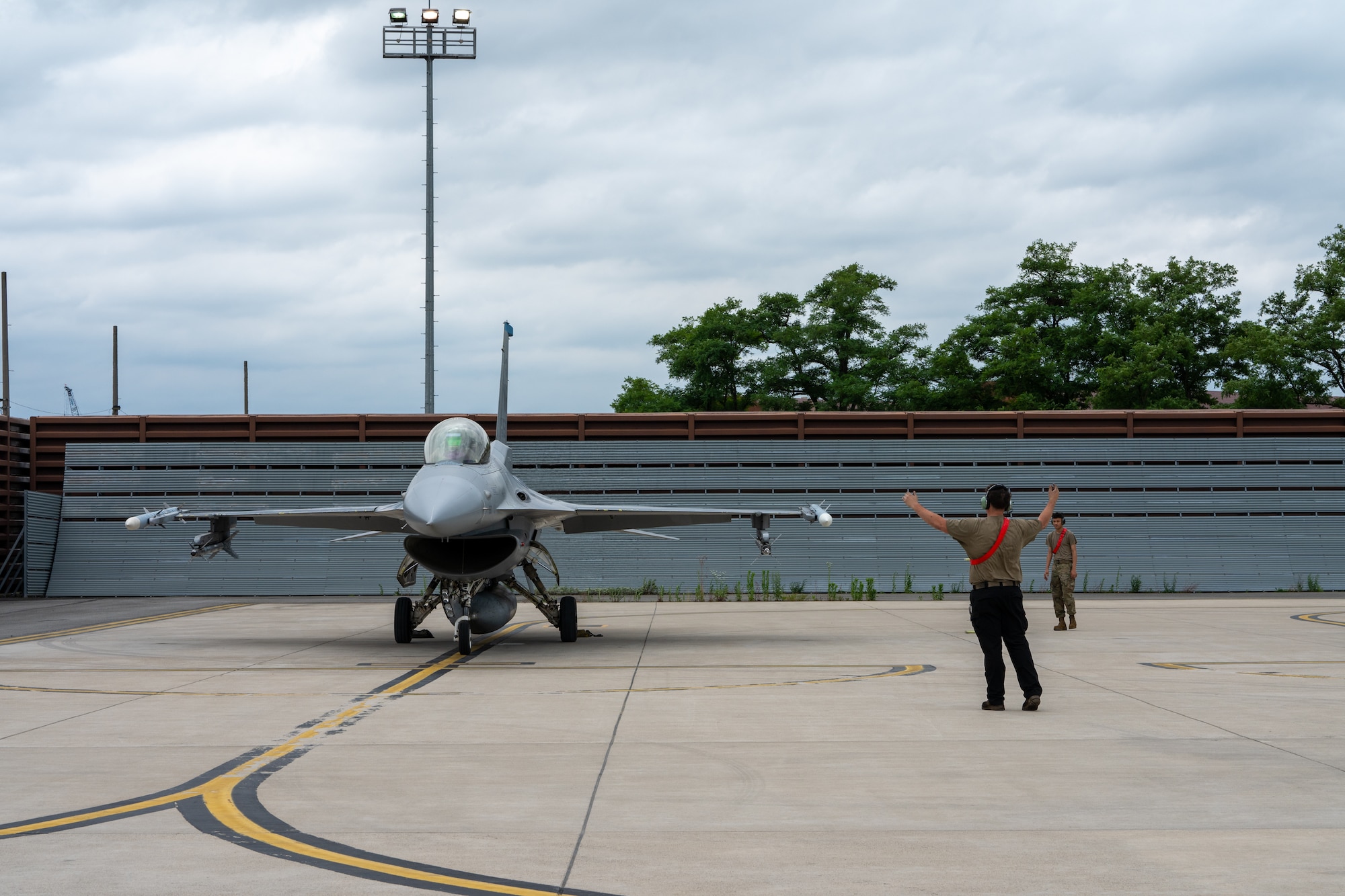 A maintainer marshals an aircraft to park.
