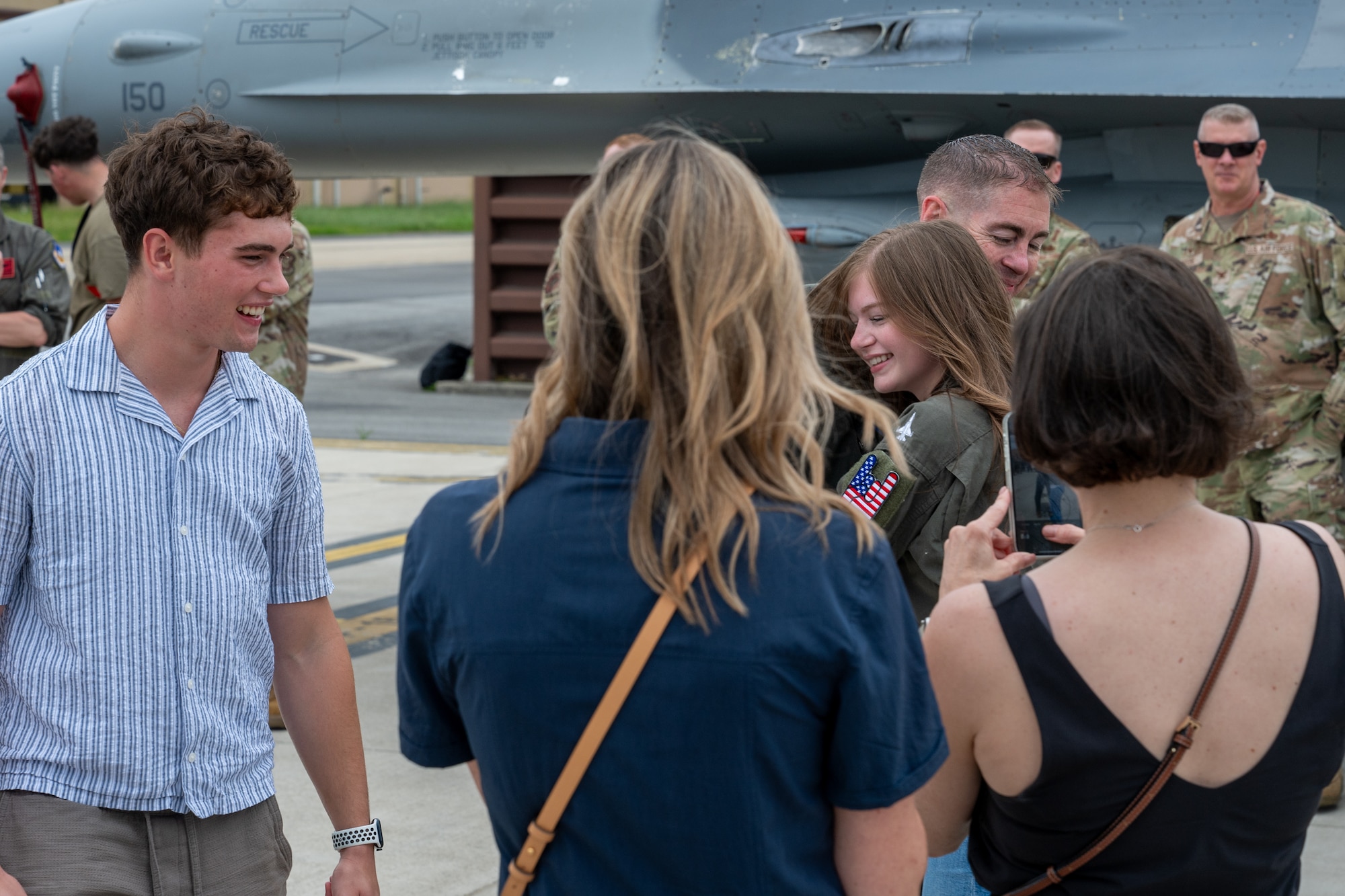 A deputy commander hugs family members after a flight.