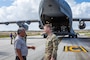Two men, one in Army uniform, speak in front of the tail end of C-17 aircraft