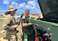 Two men in Army uniforms work on a equipment that supports electricity generation
