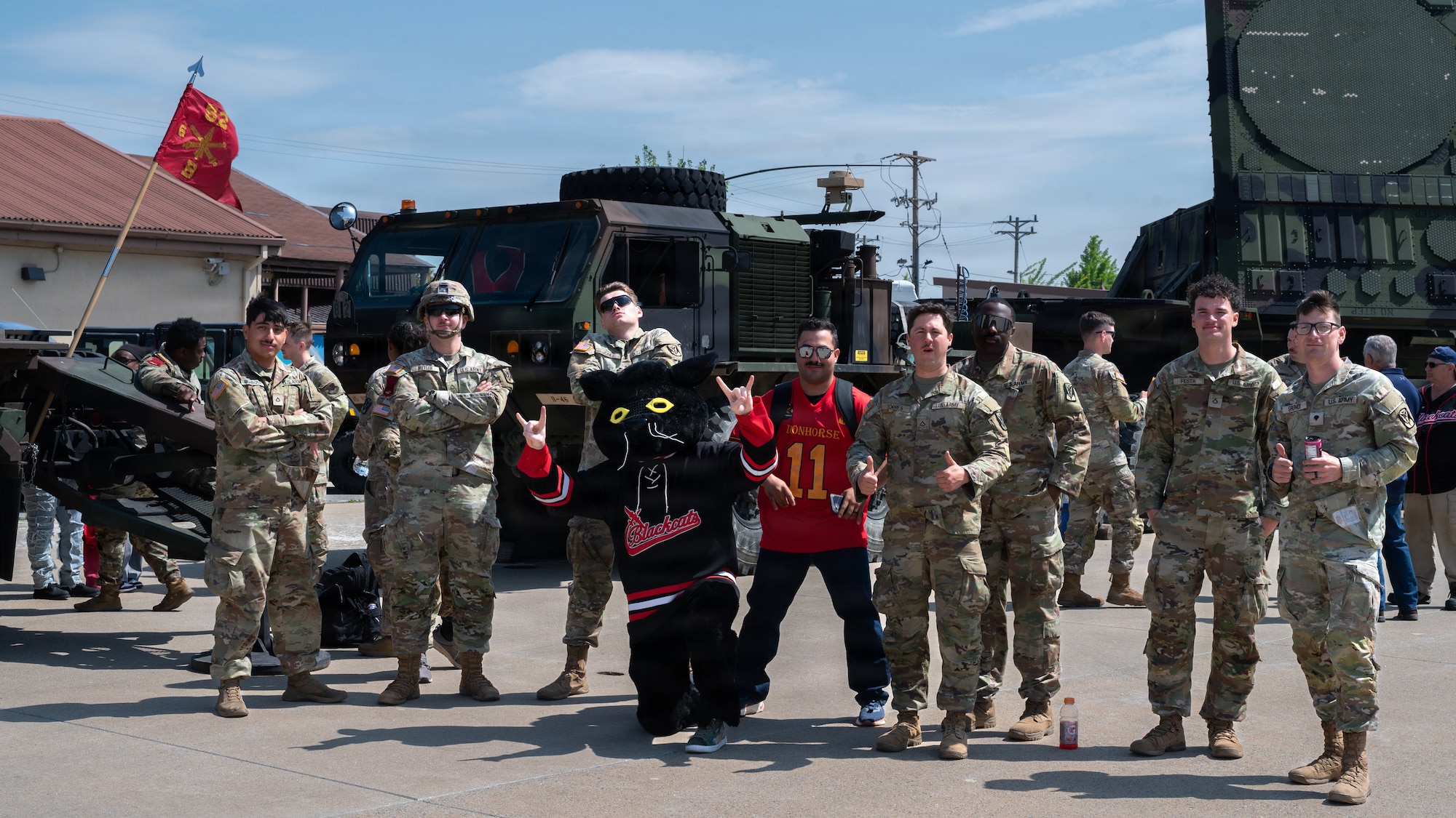 A black cat mascot and soldiers pose for a group photo.