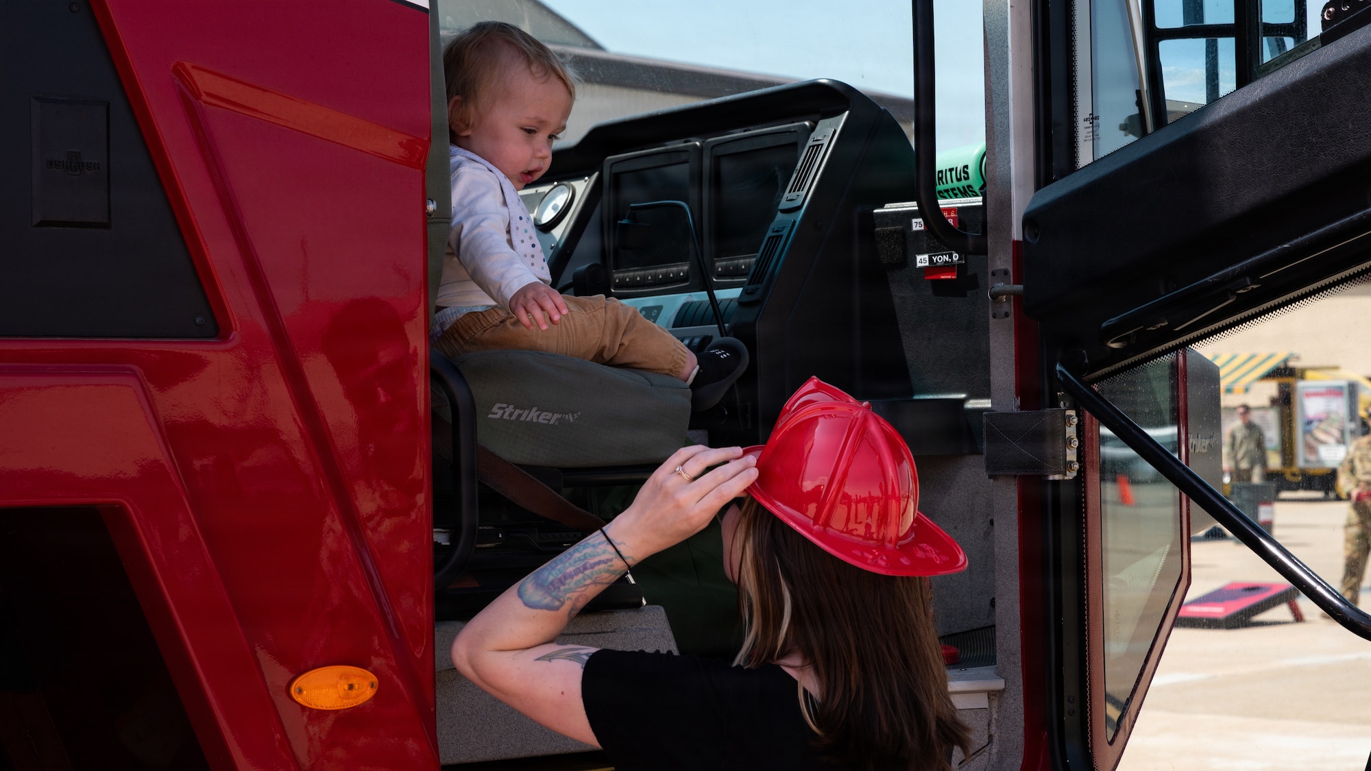 A mother and her child interact by a firetruck.