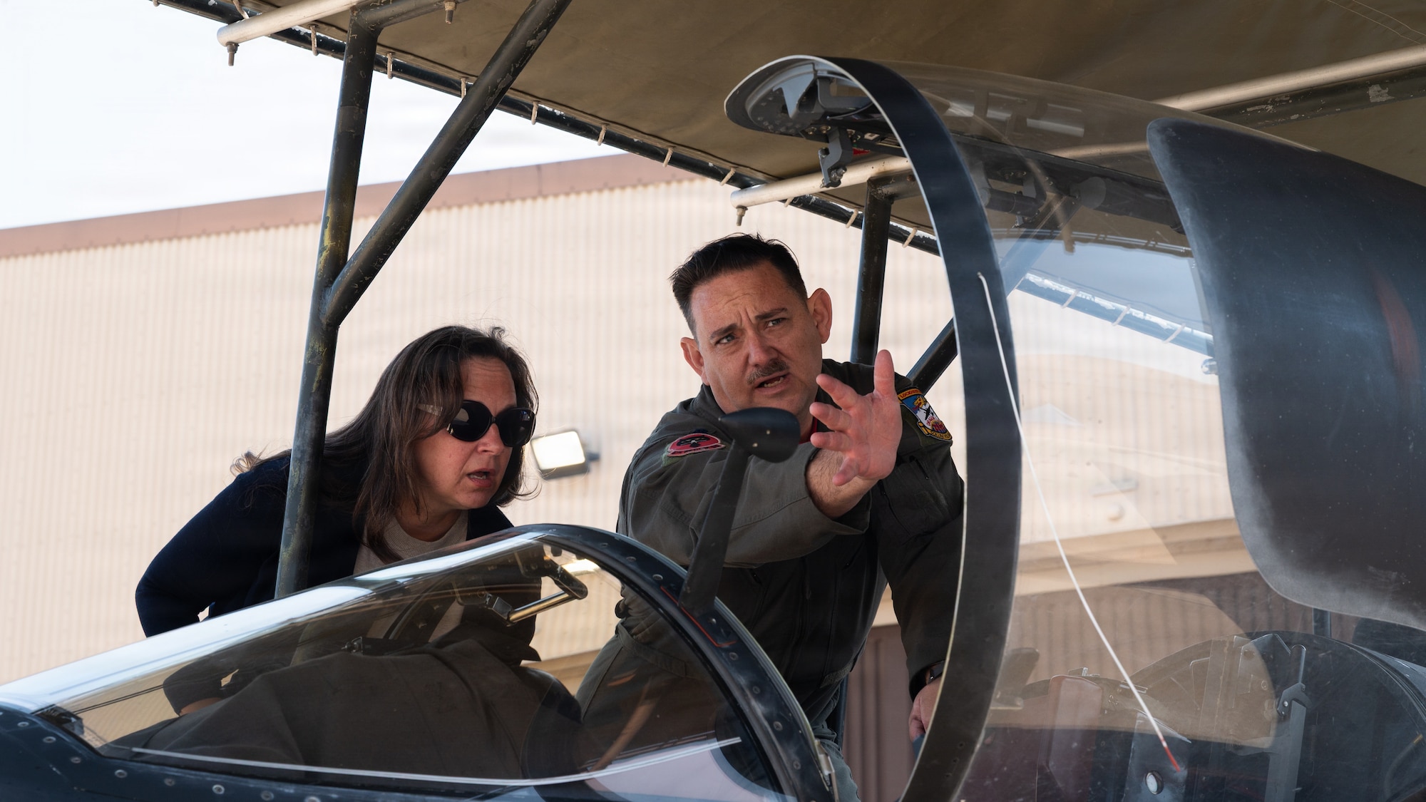Two people touring the cockpit of an aircraft.
