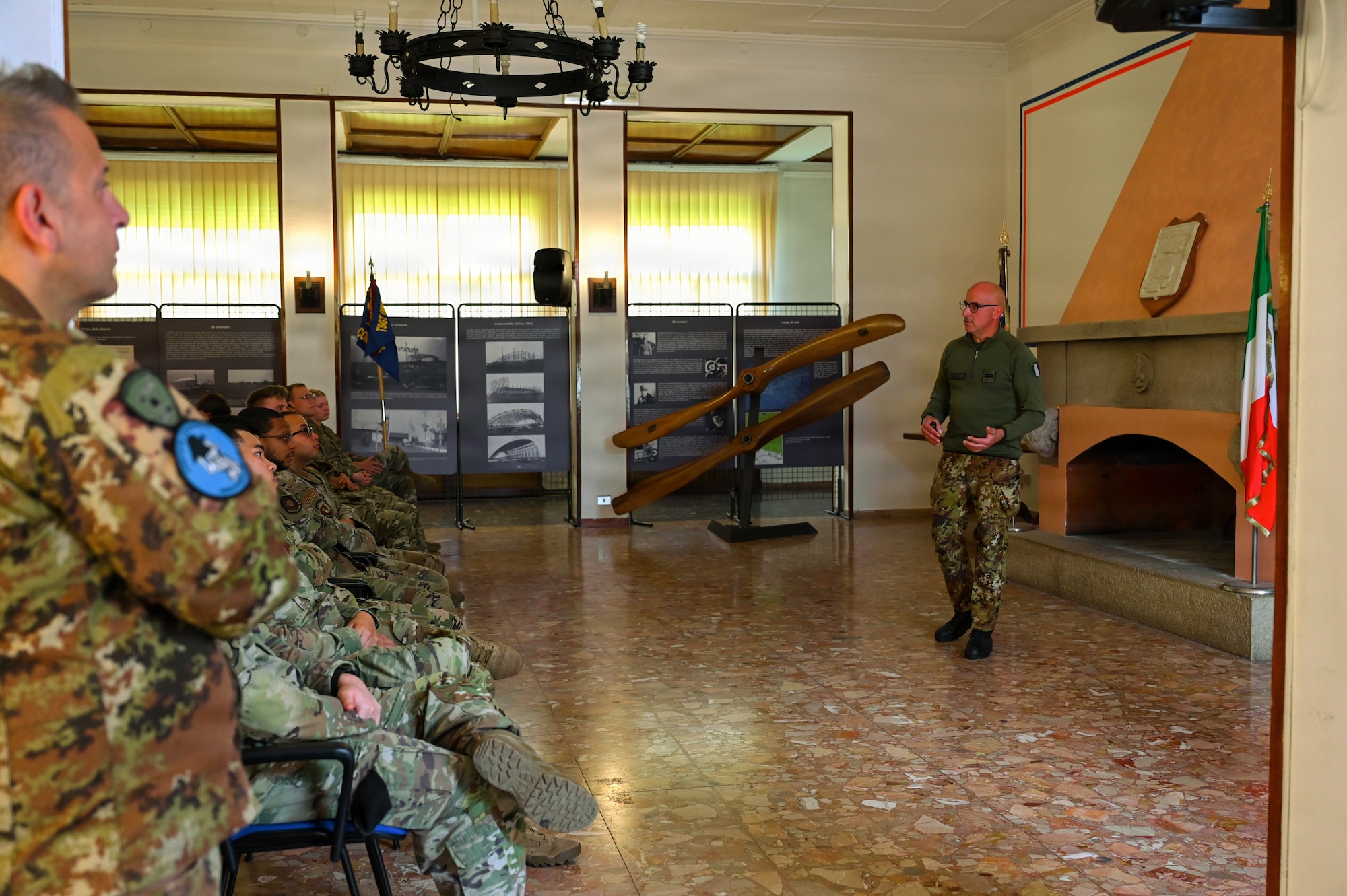 Italian air force Senior Master Sgt. Stefano Zecca, ITAF public affairs officer, briefs U.S. Air Force Airmen from Airmen Leadership School on the history of the 31st Fighter Wing and how it came to be activated at Aeroporto Pagliano e Gori at Aviano AB, Italy, May 12, 2026.