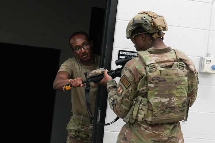 an instructor grabs the barrel of a rifle that is being held by an airman