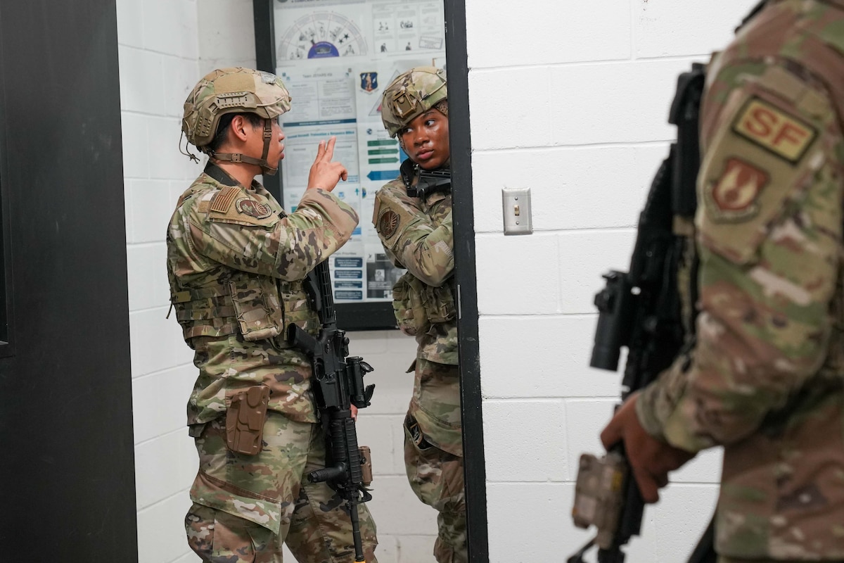 an Airman holds up two fingers to show his partner the casualty count so she can report it over the radio
