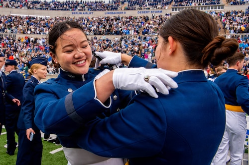 Graduates assist each other in pinning on their second lieutenant insignia following the U.S. Air Force Academy Class of 2026 graduation ceremony at Falcon Stadium in Colorado Springs, Colo., May 28, 2026. A total of 931 cadets received commissions as second lieutenants in the U.S. Air Force and U.S. Space Force.  (U.S. Air Force photo/Adalyn Greene)