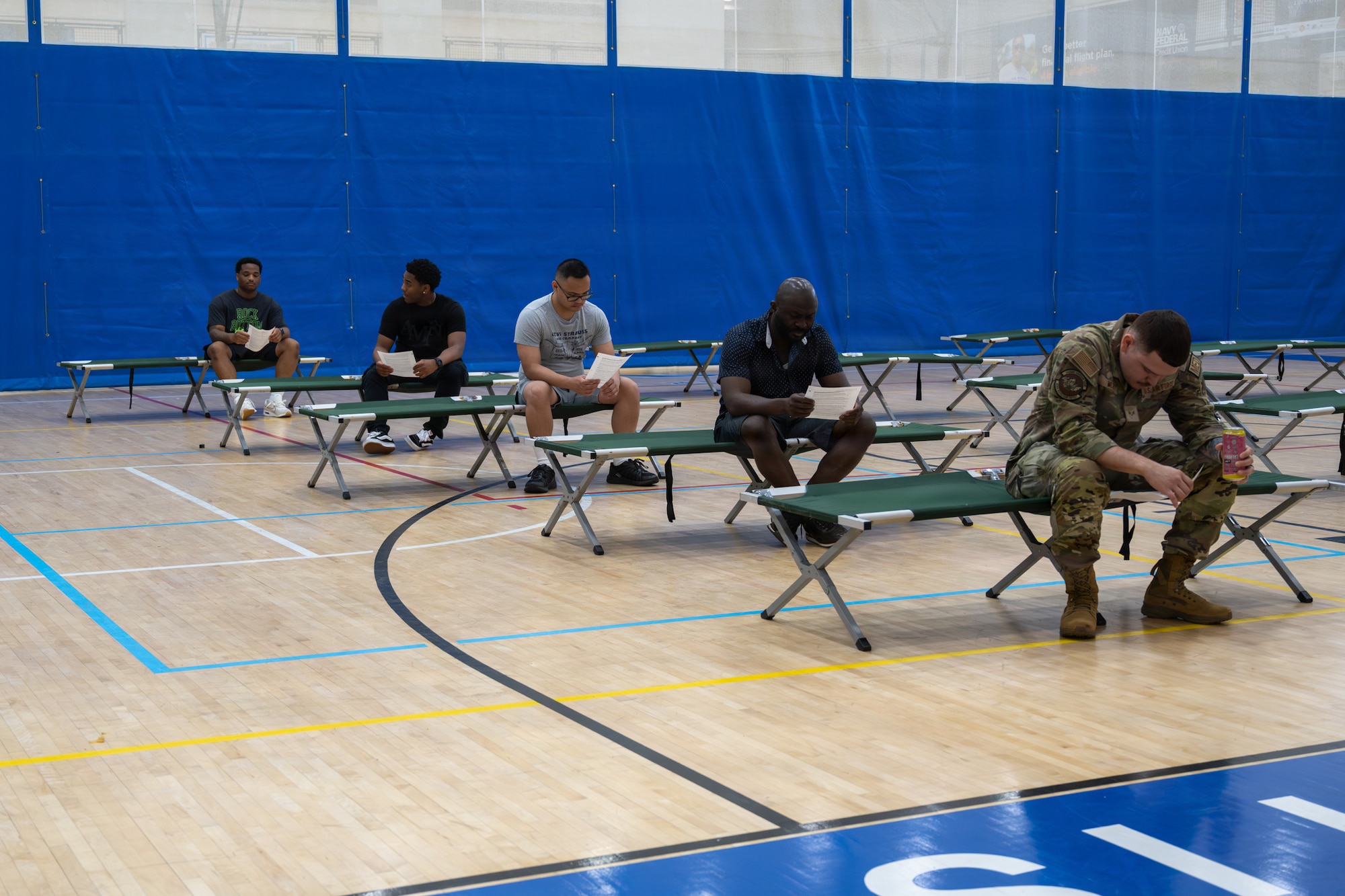 A group of people sit on cots.